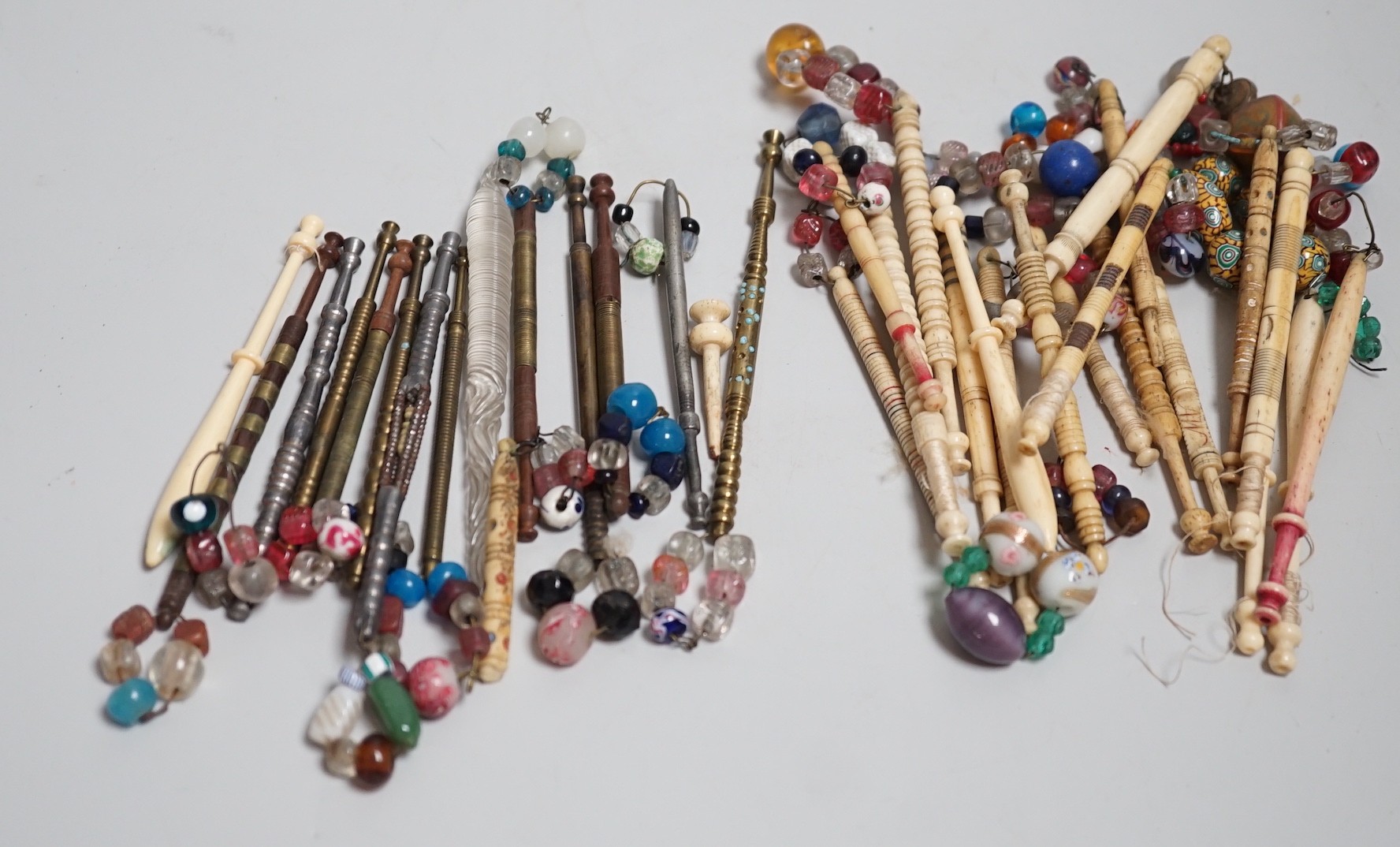 Twenty ornate 19th century turned bone and beaded topped lace bobbins and eleven ornately turned metal lace bobbins, glass bobbin and 3 broken bobbins (34)